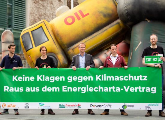 Fünf Menschen stehen vor einem Plakat, mit der Aufschrift "Keine Klagen gegen Klimaschutz - Raus aus dem Energiecharta-Vertrag