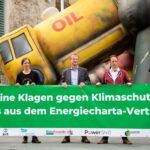 Cinco personas se paran frente a un cartel con la inscripción "No hay demandas contra la protección del clima - Fuera del Tratado de la Carta de la Energía"