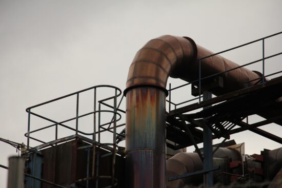 Dickes Metallrohr oder Pipeline mit Gerüst Perspektive von unten vor grauem Himmel