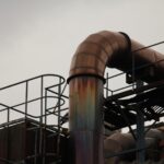 Tubo o tubería de metal grueso con andamios, perspectiva desde abajo frente al cielo gris