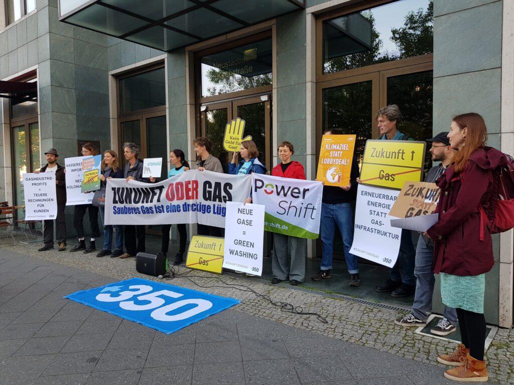 Menschen stehen mit Protestschildern vor dem Gebäude des Lobbyverbandes “Zukunft Gas”