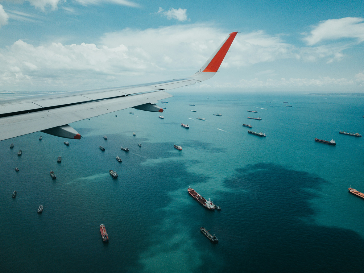 Flugzeug über Containerschiffe